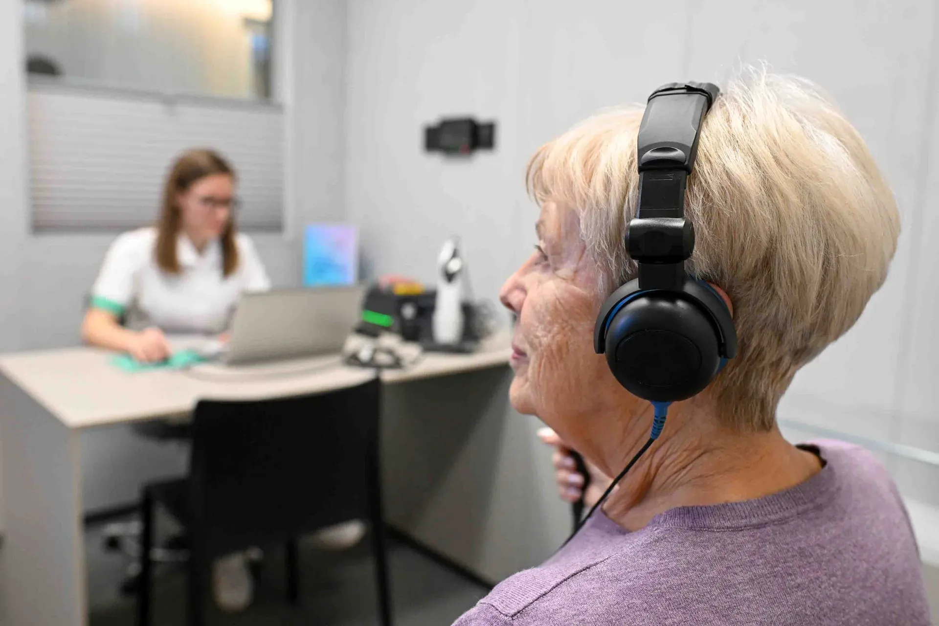 Avdiologinja s pacientom prilagaja slušni aparat Danavox
